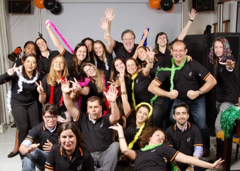 grupo de 21 pessoas posando para foto em clima animado, trajando acessórios de festa